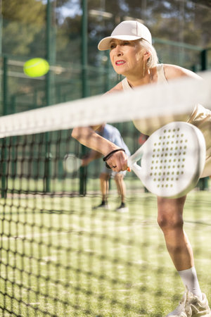 Old woman playing Padel Tennis in open-air tennis courtの写真素材