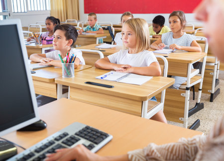 Diligent tweens studying in classroom with female teacherの写真素材