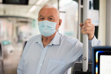 Elderly man standing in tramの写真素材