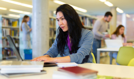 Asian woman student studies in the library on a laptopの写真素材
