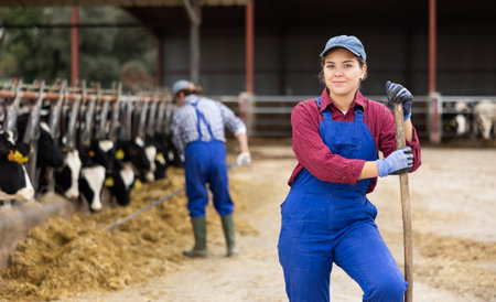 Young woman farmer posing while feeding cows at farmの写真素材