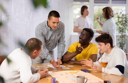 Group of enthusiastic men playing board game sitting around table