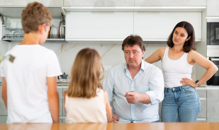 Angry parents scolding two children standing in front of themの写真素材