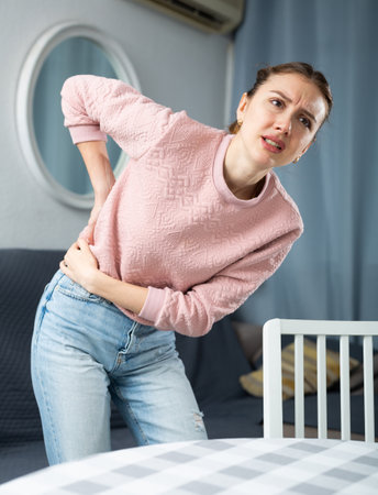 Woman suffering from back pain at homeの写真素材