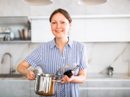 Portrait of a housewife preparing soup in a pot in kitchen