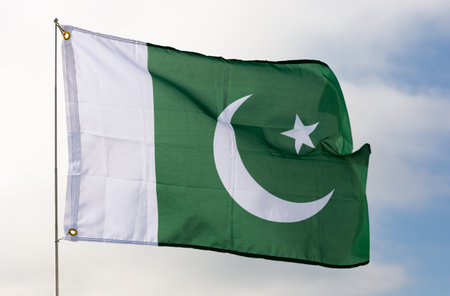 National flag of Pakistan fluttering on flagpole against skyの写真素材