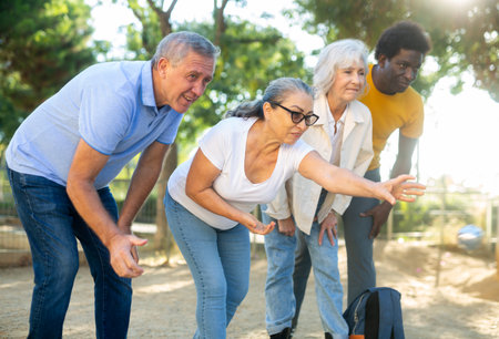 Cheerful males and females playing petanque in park on holidaysの写真素材