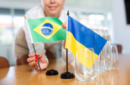 Unrecognizable girl sets midget flags of Ukraine and Brazil before international negotiationsの写真素材
