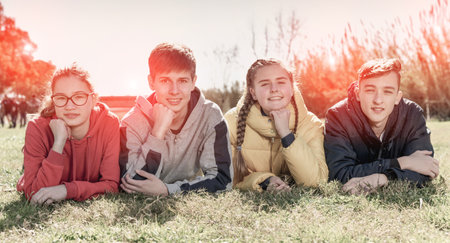 Happy teenagers laying on green lawnの写真素材
