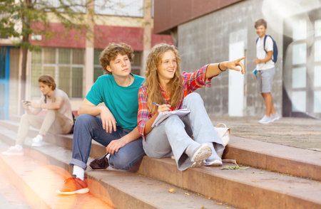 Girl points her finger to guy on the street during break in collegeの写真素材