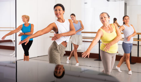 Group of active women practicing energetic dance in a studio