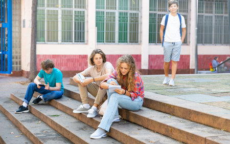 Teenage boy and girl sitting on steps near schoolの写真素材