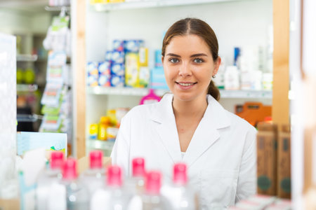 Portrait of a young female pharmacist standing behind the counter of a pharmacyの写真素材