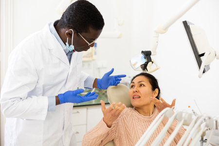 Asian woman with toothache sitting in chair at dentist appointmentの写真素材