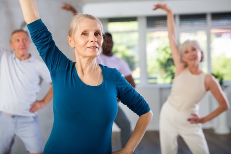 Mature men and women practicing Rock n Roll dance in training hallの写真素材