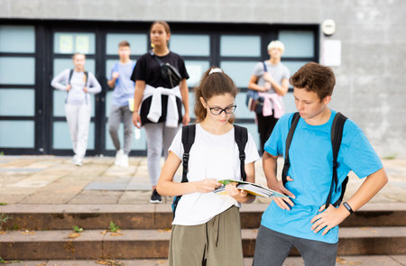 Students holding bags and talking while walkingの写真素材