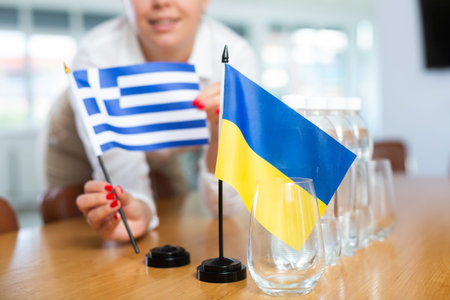 Unrecognizable girl sets midget flags of Ukraine and Greece before international negotiations