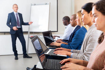 Side view of managers group working at laptops in officeの写真素材