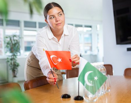 Young woman puts Turkey and Pakistan flags on table in officeの写真素材
