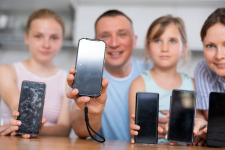 Happy family of four showing screens of their phones
