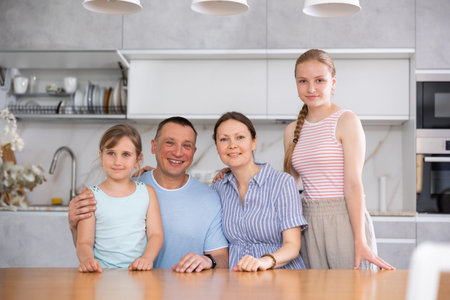 Happy family of four people is posing at kitchen table