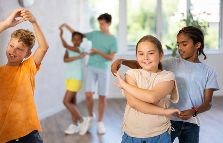 Active preteen children practicing Ballroom dances in pairs in training hall