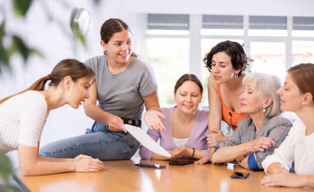 female student sits on table,holds paper documents in hands and actively promotes version taskの写真素材