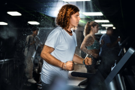 Adult man ldoing cardio workout on treadmill in gymの写真素材