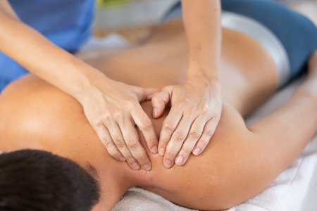 Man receiving massage relax treatment close up. Masseur hands doing back massage in spa centerの写真素材