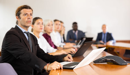 Man in suit attending meeting and using laptop
