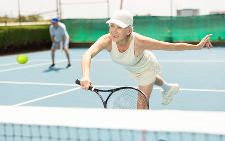Senior woman plays tennisの写真素材