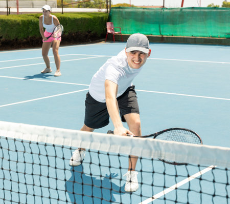 Man in shorts and t-shirt playing tennis on court. Racket sport training outdoorsの写真素材
