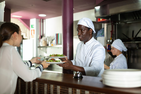 Chef giving out ready salads to waitressの写真素材