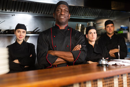 Team of confident chefs look at camera on kitchen restaurantの写真素材