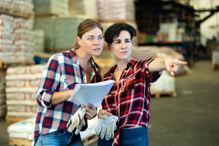 Women working in warehouse, checking documents and poitning fingerの写真素材