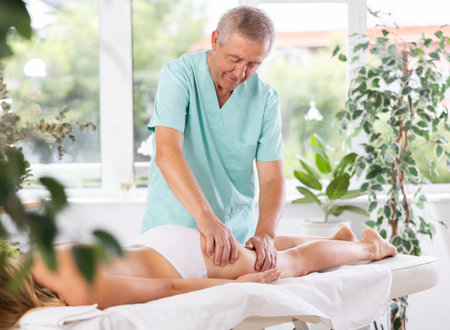 Skilled old masseur conducting hip massage for woman clientの写真素材