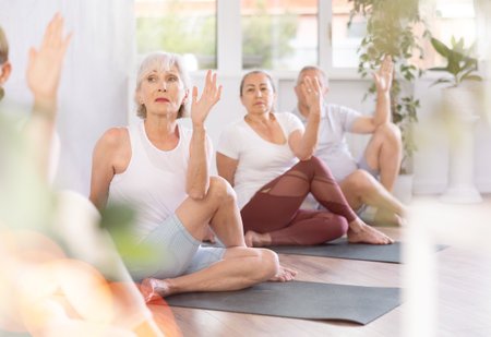 Group of elderly people doing yoga on mat in studioの写真素材