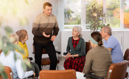 Male psychologist conducting a group session with mature clients