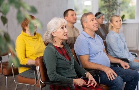 Interested aged woman listening to lecture in auditorium
