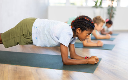 Young african boy doing pilates in group of children