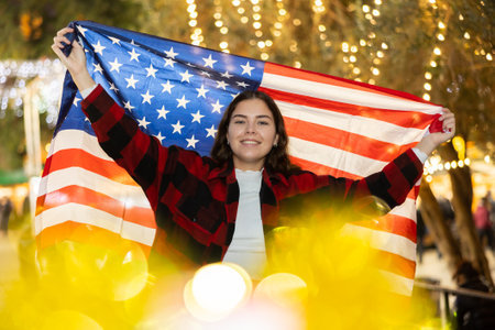 Woman waving USA flag at street new year fairの写真素材