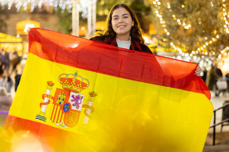 Woman waving Spanish flag at street new year fairの写真素材