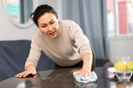 Woman householder using rag to wash tableの写真素材