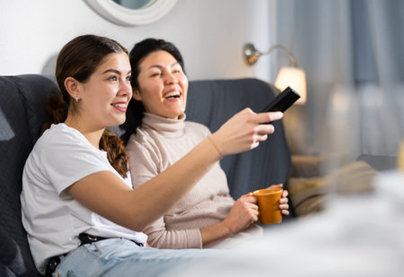 Two women relaxing at home watching TV