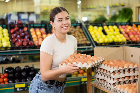 Woman choosing and buying fresh eggs at grocery storeの写真素材