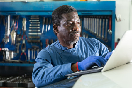 African mechanic man using a laptop computer checking car in workshopの写真素材