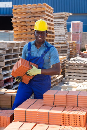 Worker stacking bricks in warehouse of building materials clpseup
