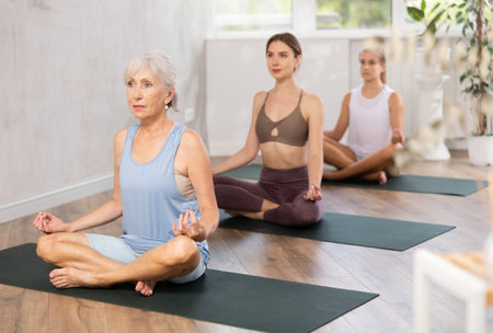 Women three generations practise yoga, meditation in lotus position in fitness studioの写真素材