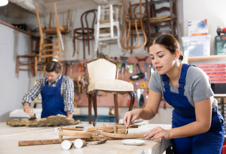 Young female furniture maker working on vintage chair parts in workshopの写真素材