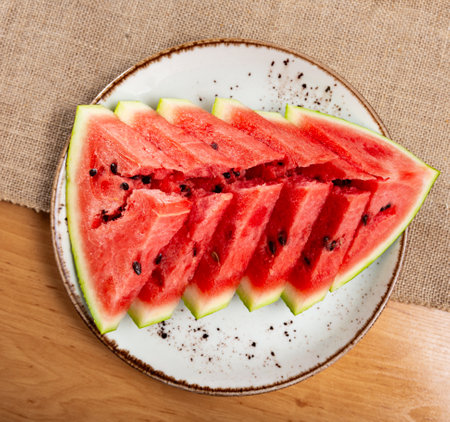 Ripe red sweet watermelon slices on plate on tableの写真素材